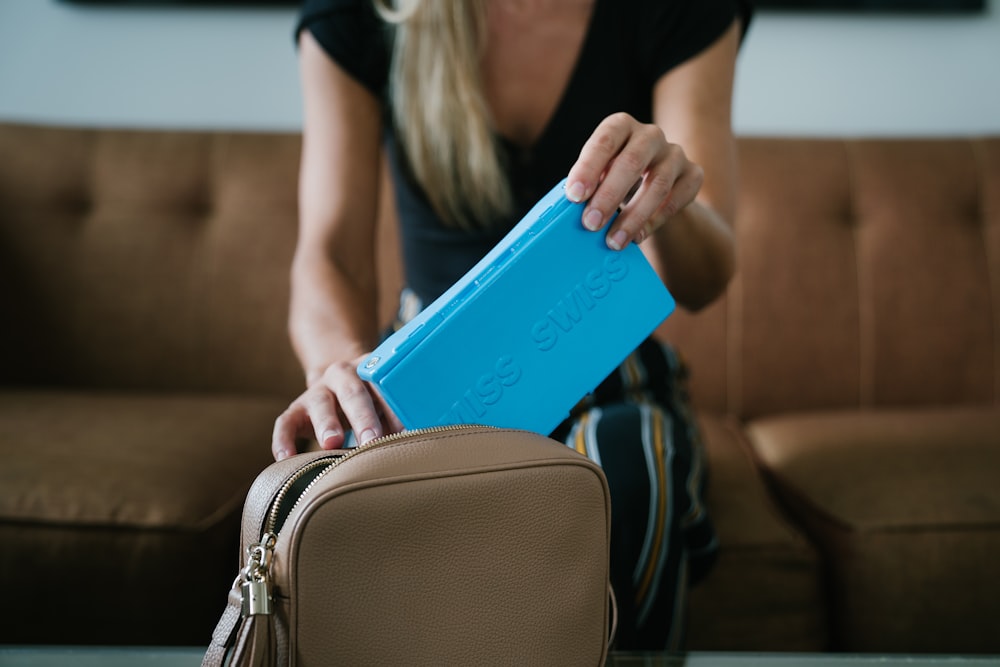 mulher na camisa preta que segura o caso azul do computador do tablet