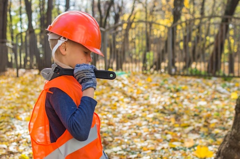 boy in orange and black jacket wearing red helmet holding black dslr camera