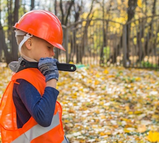 boy in orange and black jacket wearing red helmet holding black dslr camera