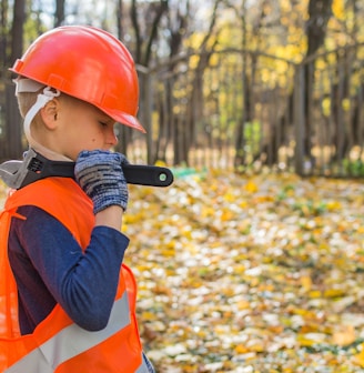 boy in orange and black jacket wearing red helmet holding black dslr camera