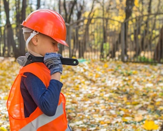 boy in orange and black jacket wearing red helmet holding black dslr camera