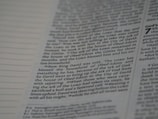 A close-up view of a page from a book, featuring columns of printed text with some words in uppercase for emphasis. The text appears neatly organized in paragraphs, and black ink is used on a white or slightly off-white paper background.
