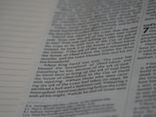 A close-up view of a page from a book, featuring columns of printed text with some words in uppercase for emphasis. The text appears neatly organized in paragraphs, and black ink is used on a white or slightly off-white paper background.
