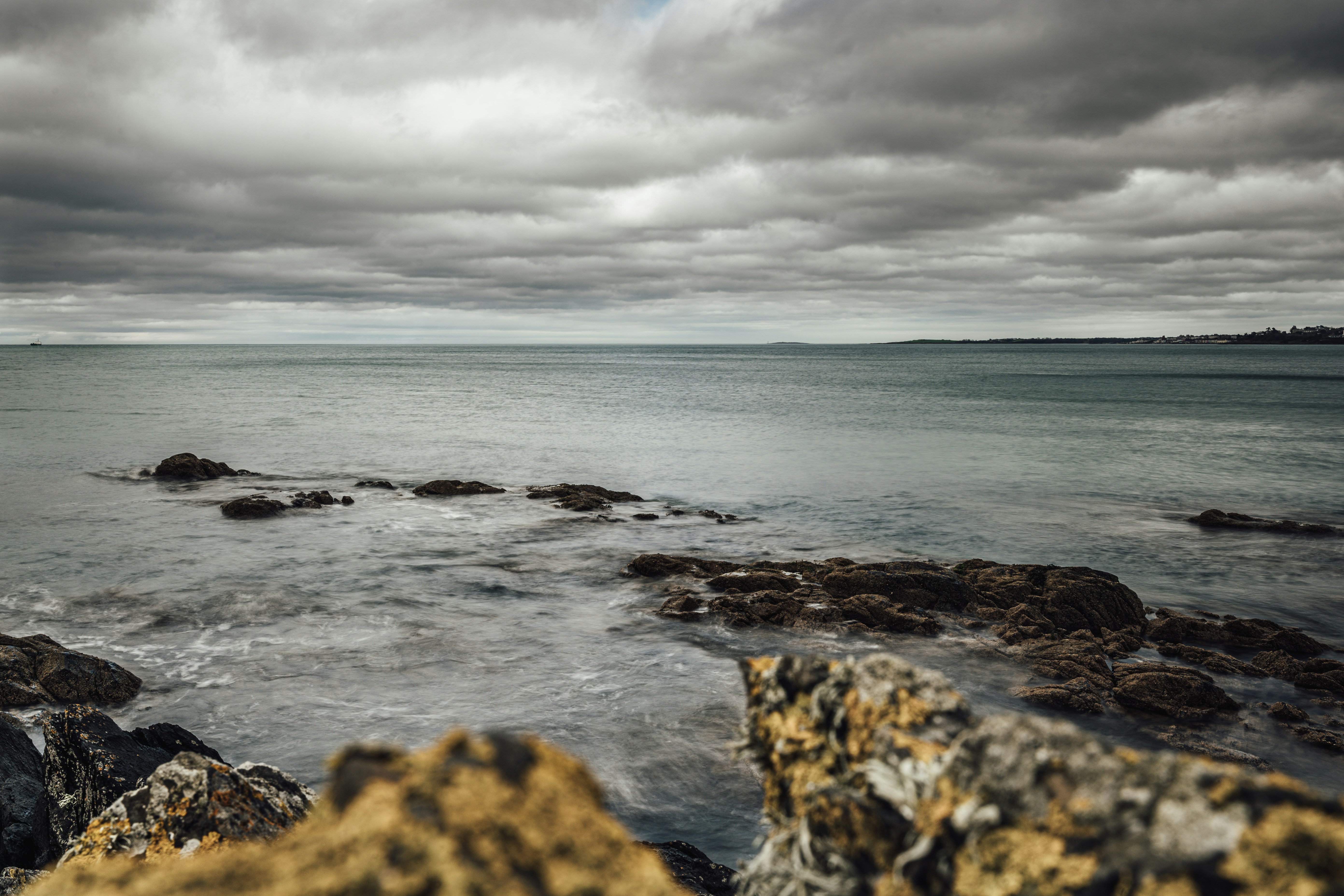 ocean waves crashing on rocks under cloudy sky during daytime