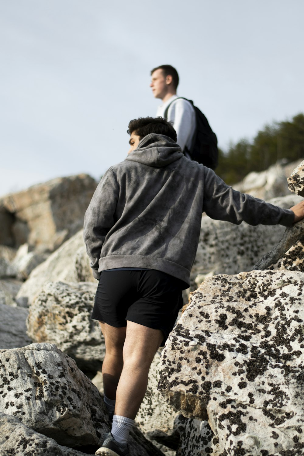 man in black hoodie and black shorts standing on rocky hill during daytime