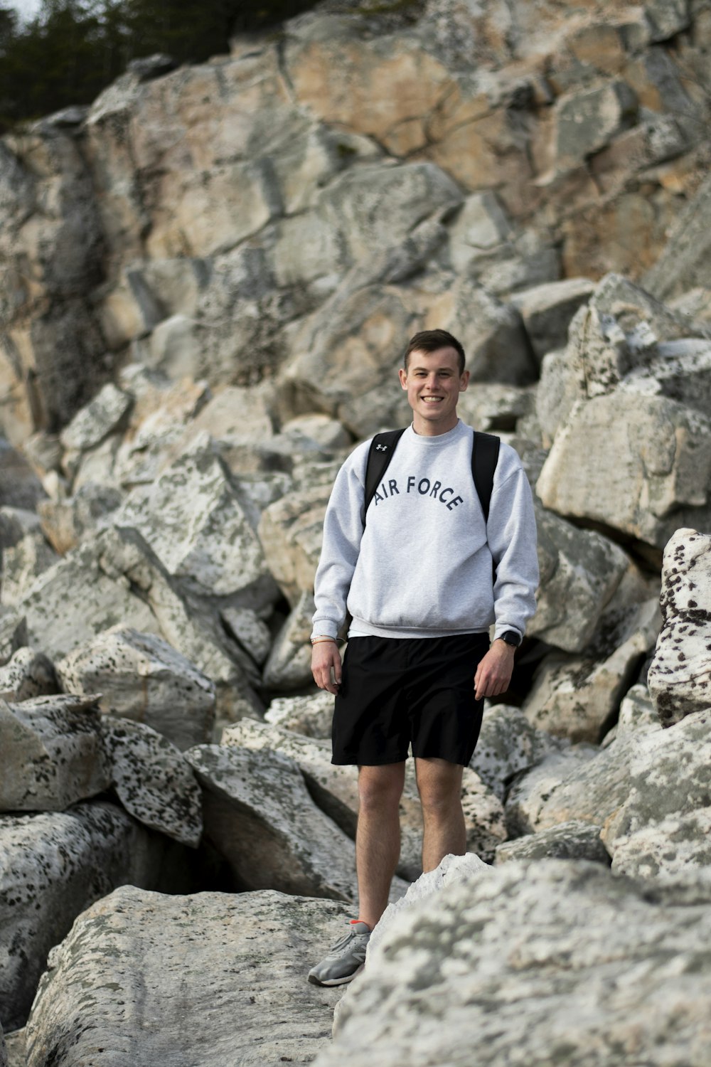 man in gray and white long sleeve shirt standing on rocky ground