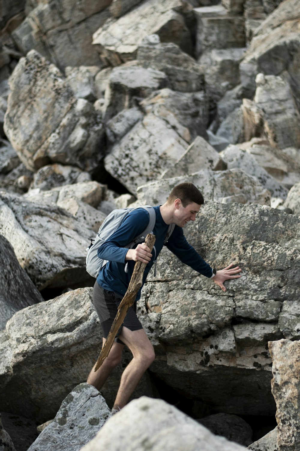 man in blue t-shirt and black pants climbing on brown rock during daytime