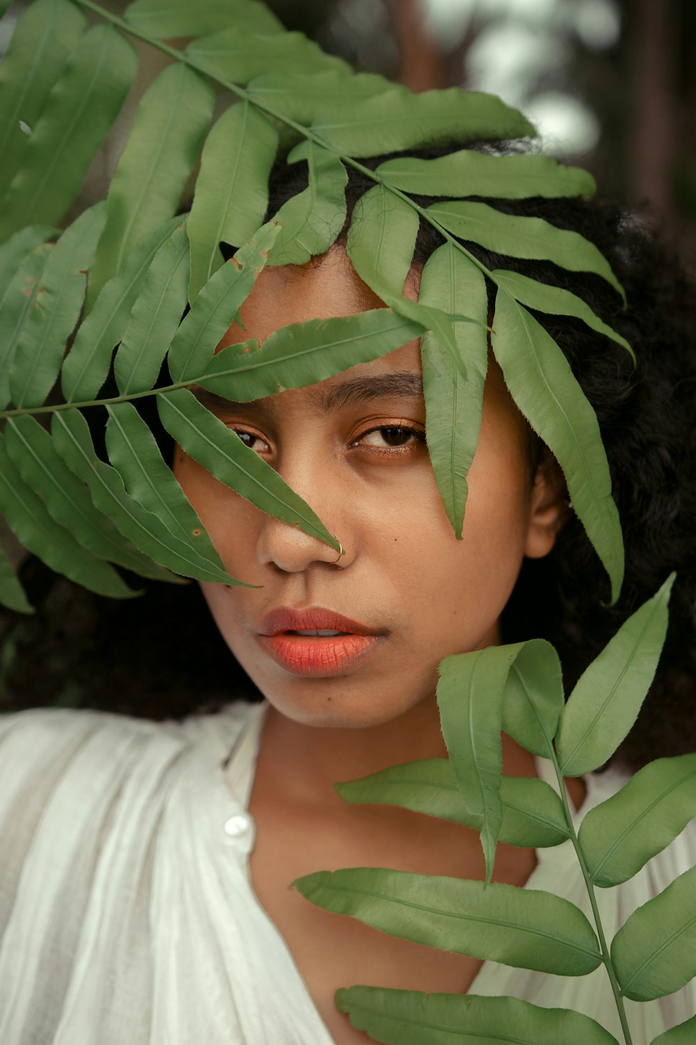 woman in white shirt holding green leaves