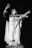 A dramatic statue of a robed figure with outstretched arms, appearing to be in a gesture of command or invoking. The figure's expression is intense and the robes suggest a historic or religious significance, with a monochrome color scheme adding to the dramatic effect.