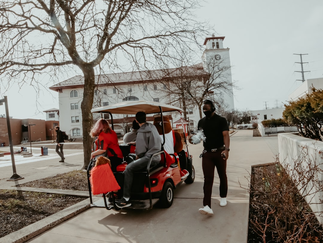 people riding on red and black golf cart during daytime