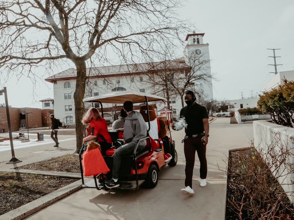 people riding on red and black golf cart during daytime