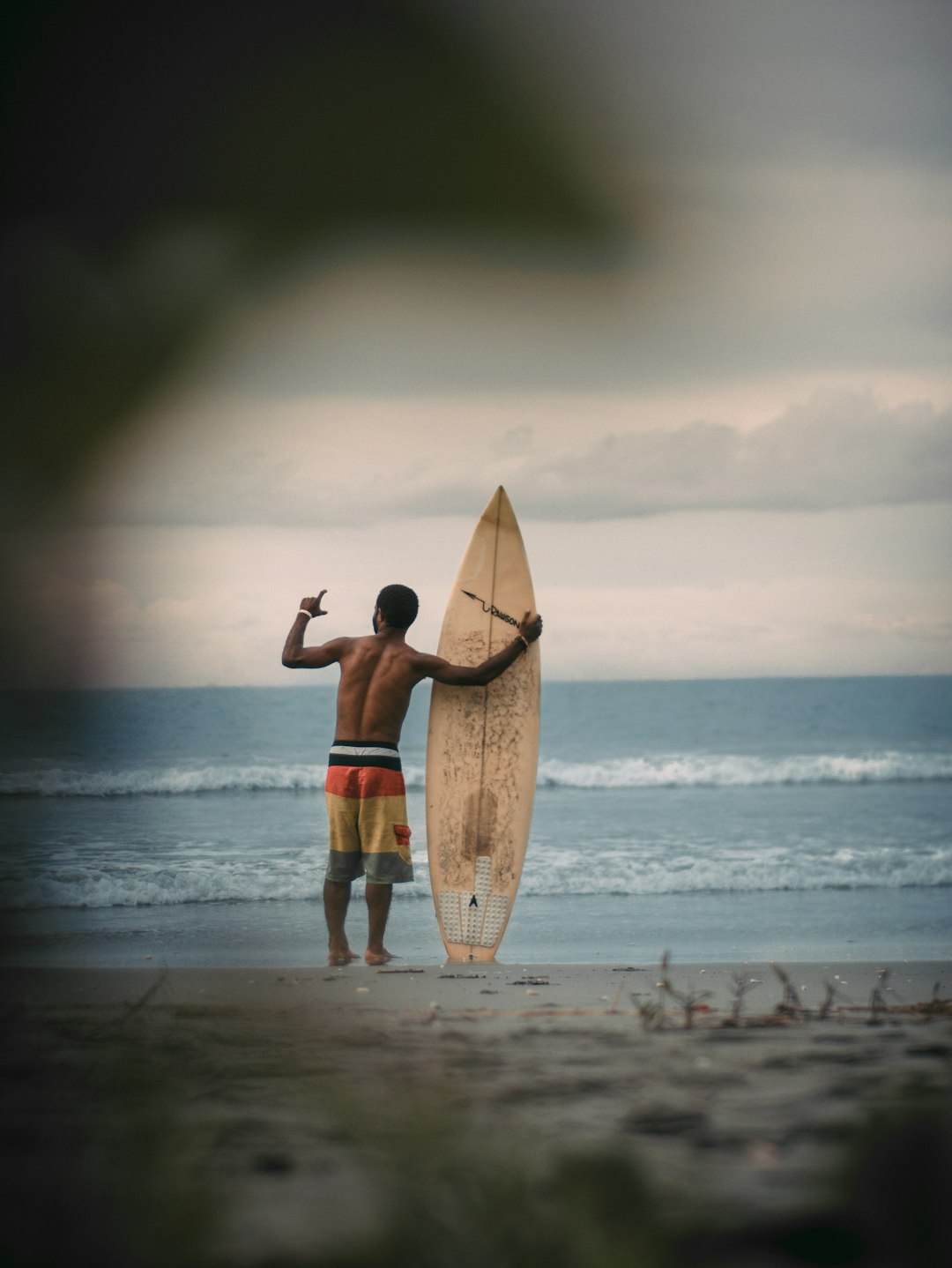 man in black shorts carrying brown surfboard on beach during daytime