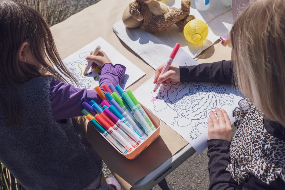 Two children making art with markers at a table