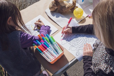 Two young children drawing with markers and crayons
