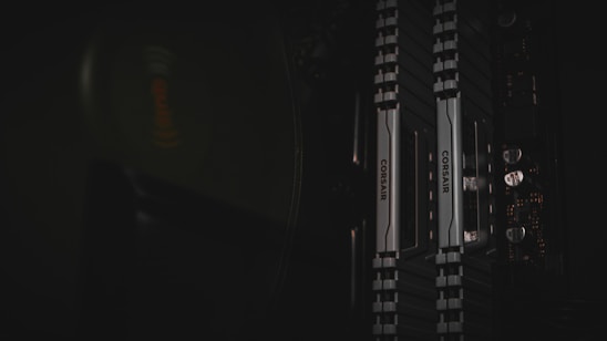 Close-up of sleek NVMe SSD and DDR5 RAM modules glowing with electric blue accents on a charcoal grey background.