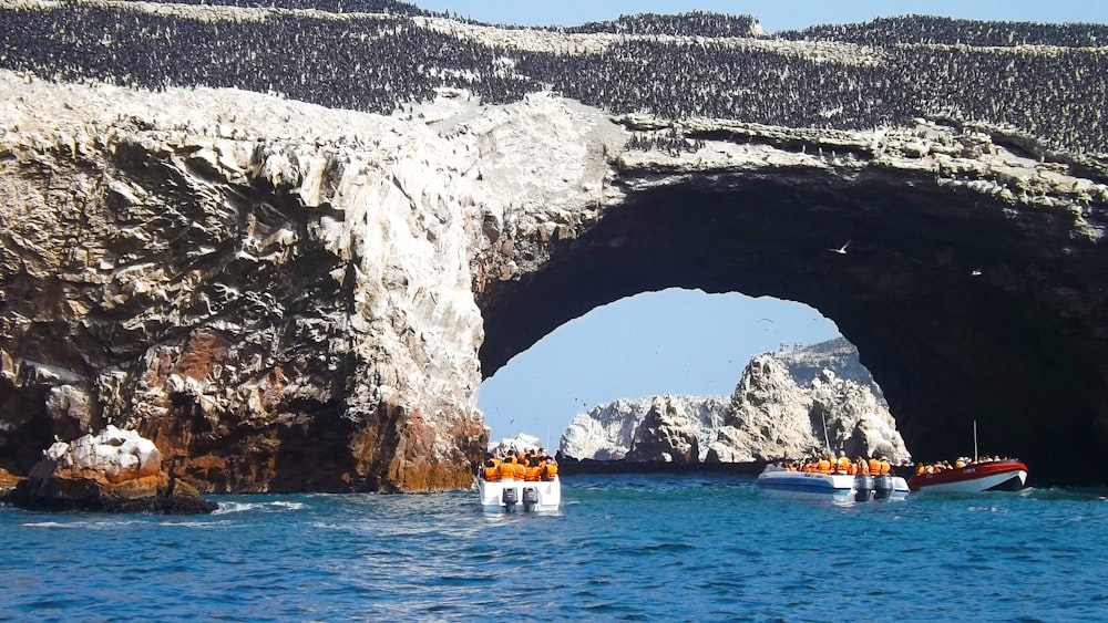 Barco blanco y naranja en el mar cerca de la formación rocosa gris durante el día