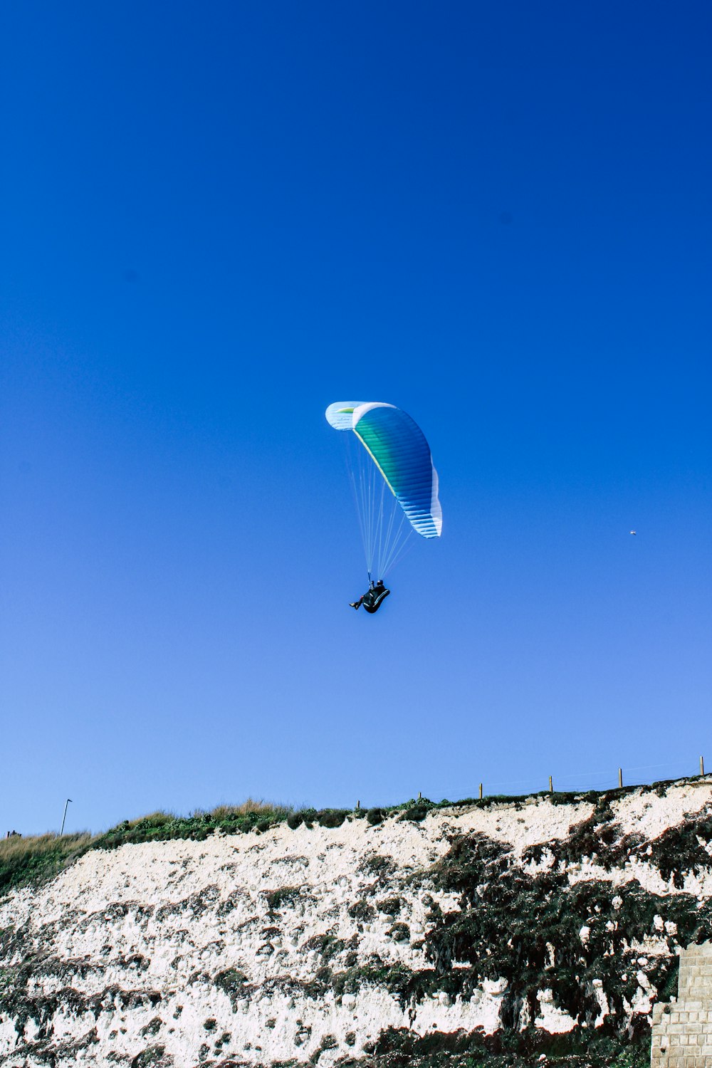 person in parachute under blue sky during daytime