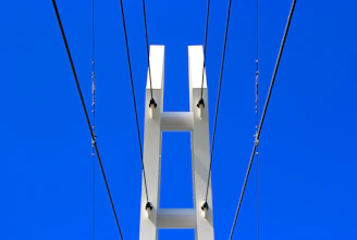 A sturdy pillar supporting a modern glass building under a clear blue sky.