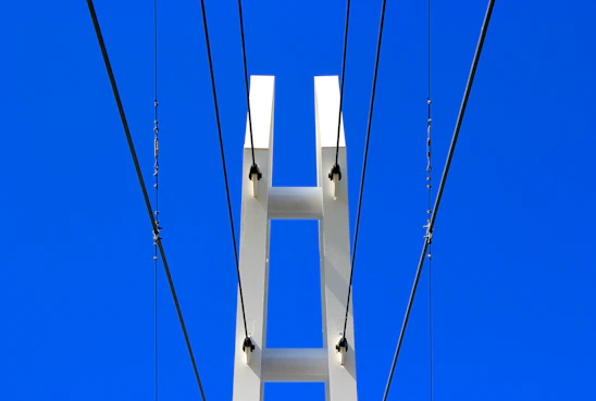 A sturdy pillar supporting a modern glass building under a clear blue sky.
