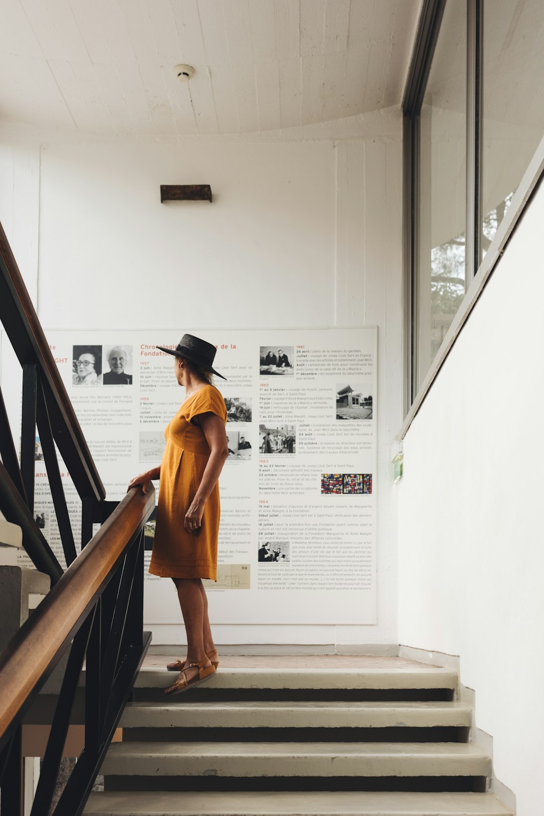 woman in black hat and orange tank top standing on stairs