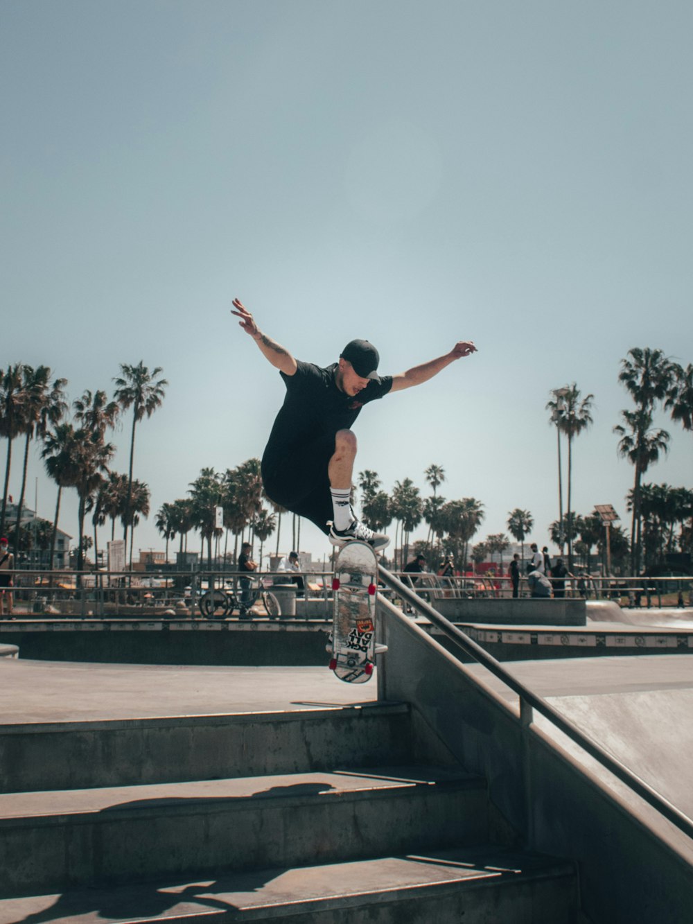 man in black tank top and black pants doing stunts on gray concrete stairs during daytime