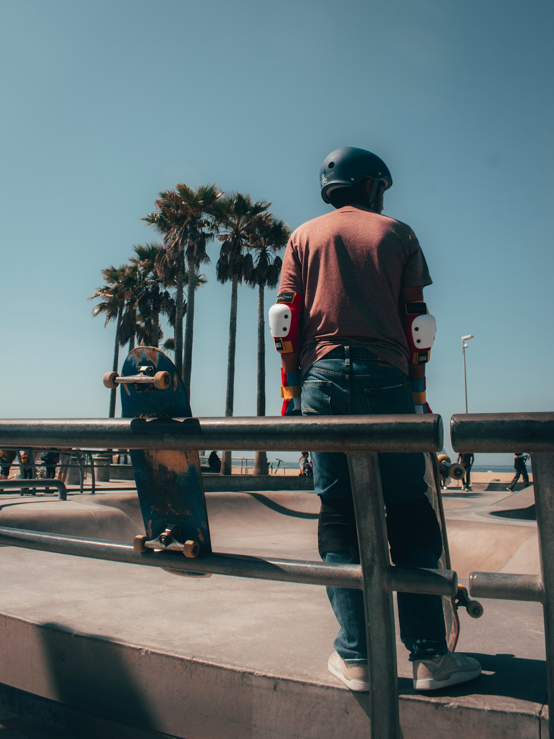 man in red shirt and black helmet standing on black metal railings during daytime