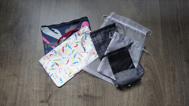 A collection of fabric bags in various sizes and patterns, stacked casually on a soft linen cloth.