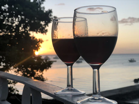 A serene Mediterranean cruise ship deck with wine glasses catching the sunset glow.