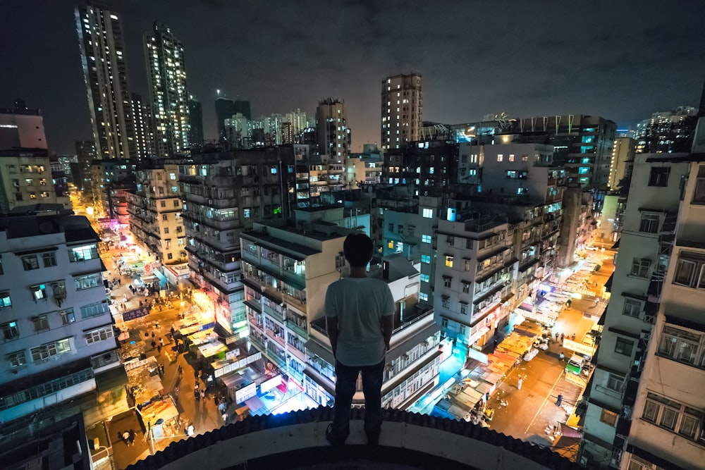 man in gray shirt standing on top of building during night time