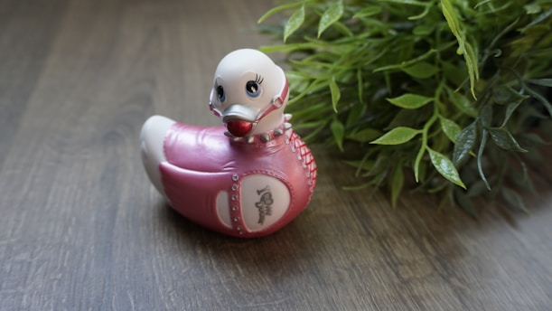 A small 3D printed duck figurine exploring a vibrant garden filled with flowers and greenery.