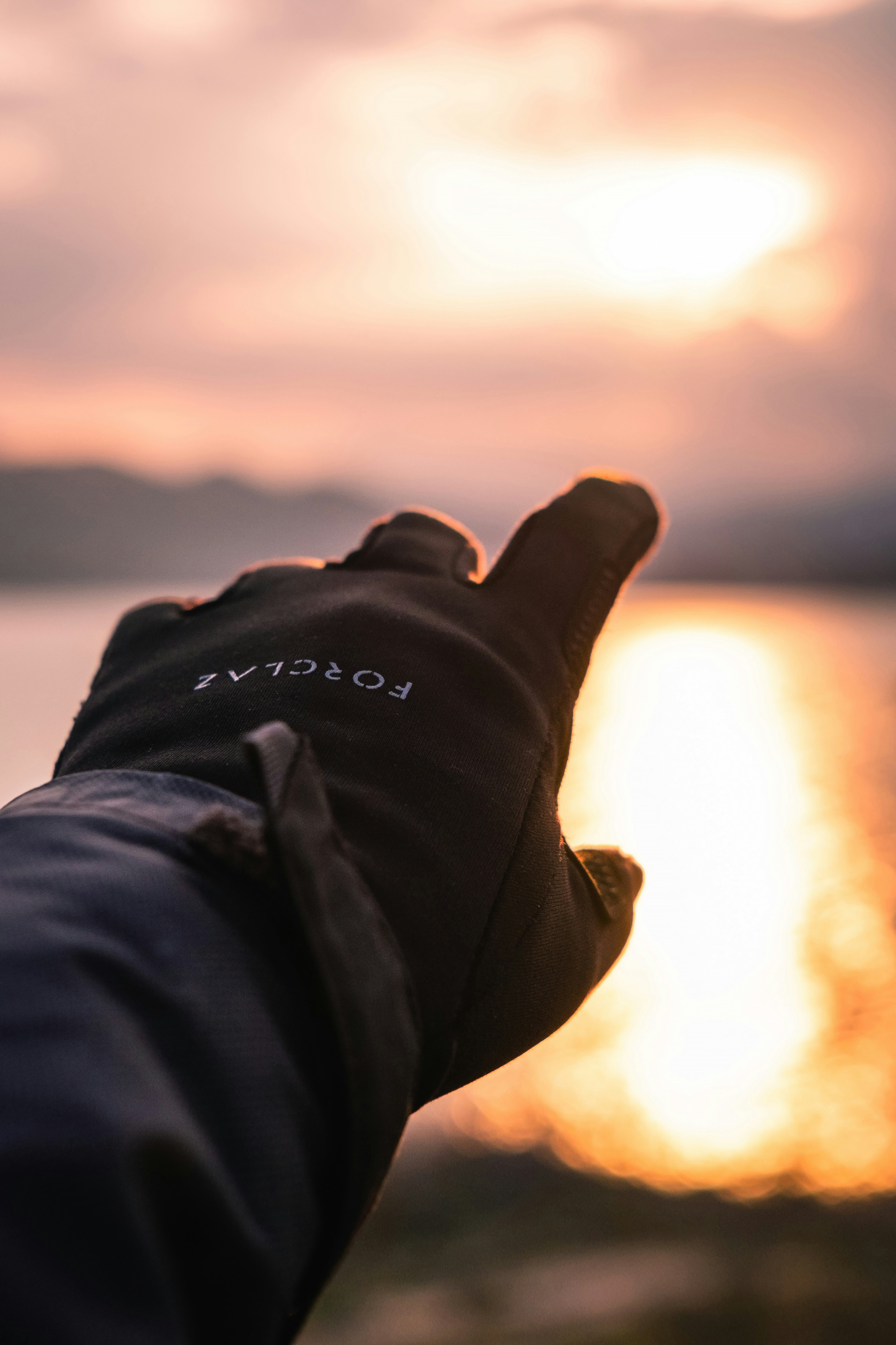 Hand in decathlon gloves on sunset background
