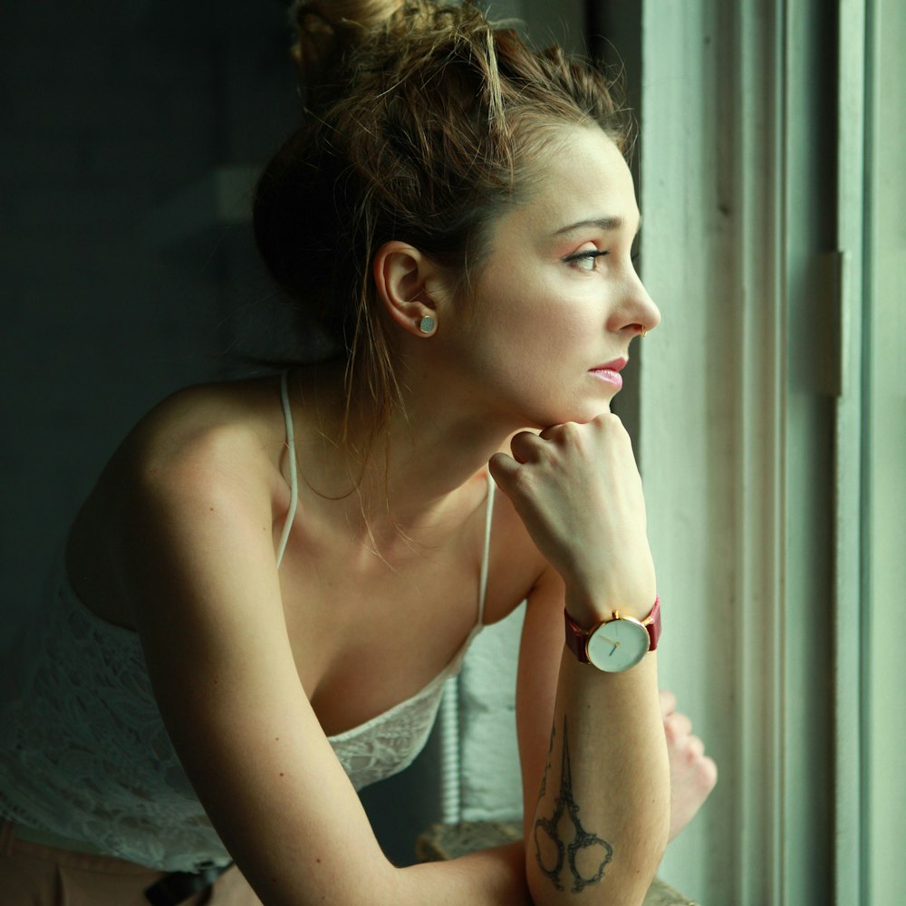 woman in white tank top leaning on wall