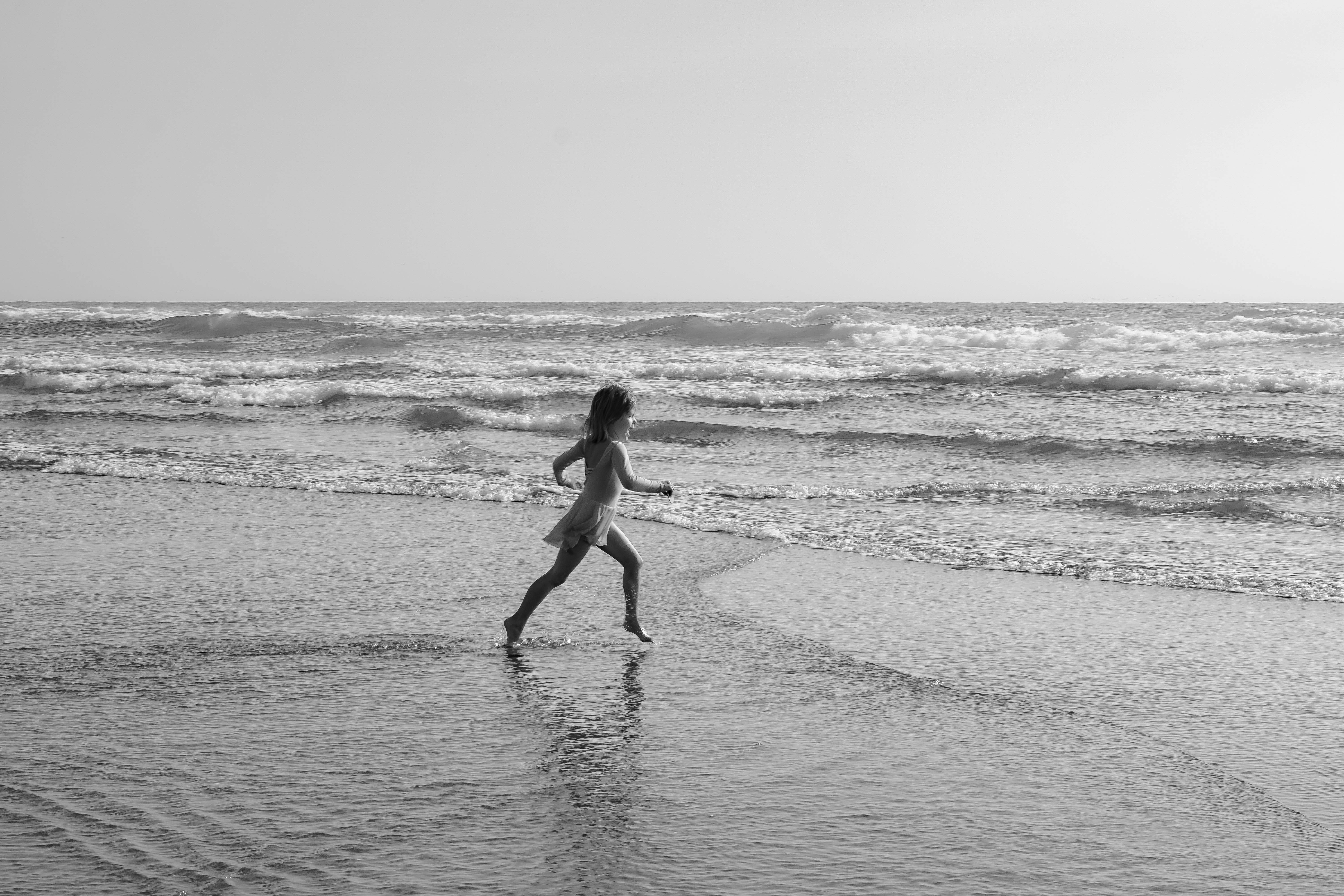 a girl runs toward the ocean.