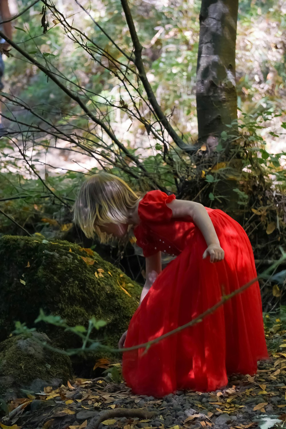 Mädchen in rotem Kleid, das tagsüber auf grünem Gras steht