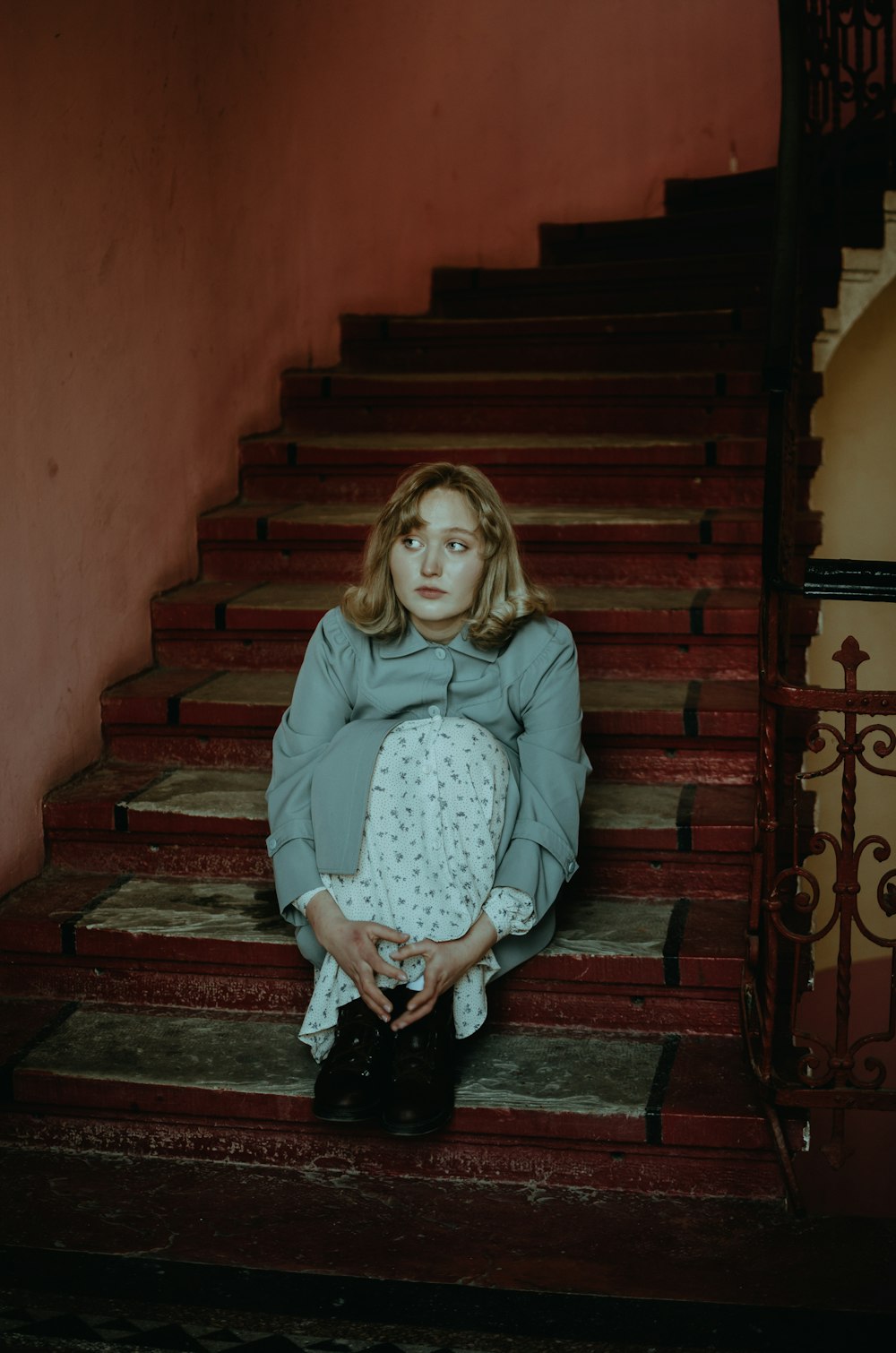 girl in gray long sleeve shirt and black pants sitting on brown wooden staircase