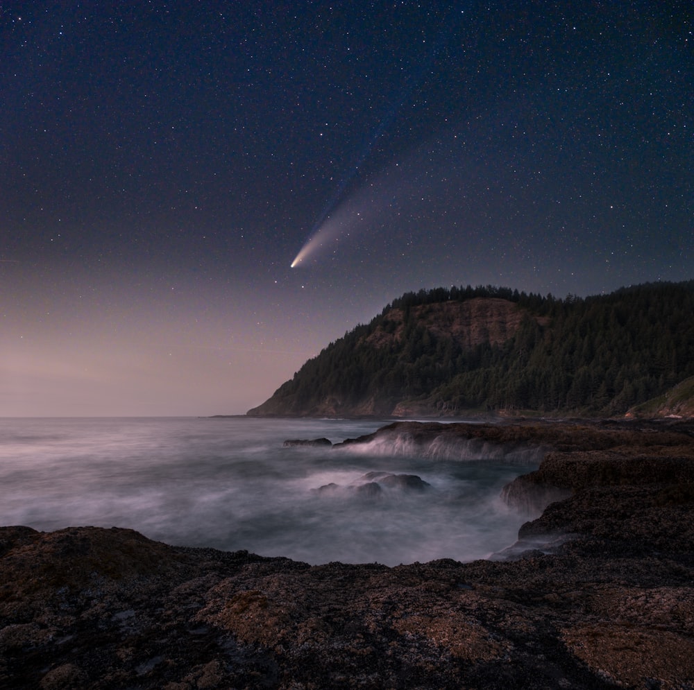 brown mountain near body of water under blue sky during night time