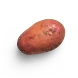 A single red potato with some soil on its surface, depicted against a white background. The potato has a rough texture with small eyes and patches of darker and lighter areas.