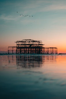 silhouette of dock on body of water during sunset