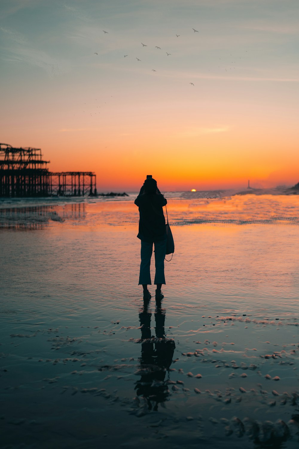 silhouette of woman standing on beach during sunset