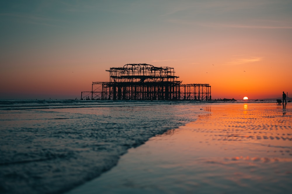 silhouette of dock on sea during sunset