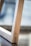 A close-up view of a wooden structure with a smooth grain. The focus is on the linear and angular design of the wood, with a blurry background suggesting a minimalist interior setting.
