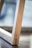 A close-up view of a wooden structure with a smooth grain. The focus is on the linear and angular design of the wood, with a blurry background suggesting a minimalist interior setting.