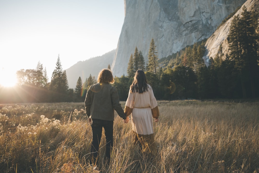 man and woman standing on brown grass field near white mountain during daytime