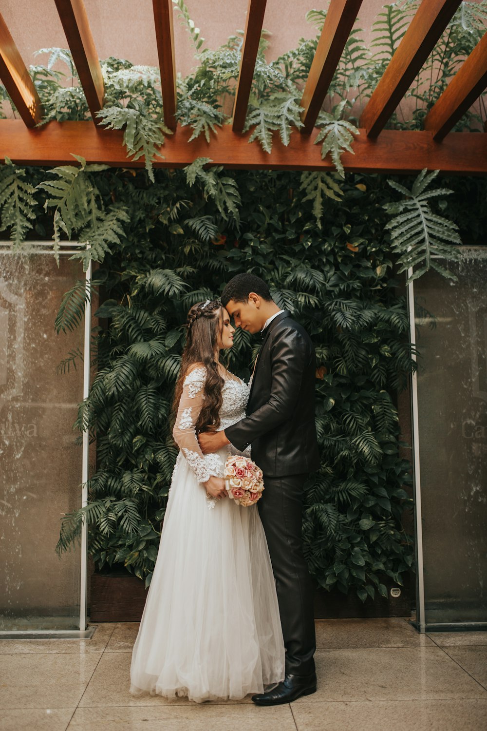 bride and groom kissing near green plant