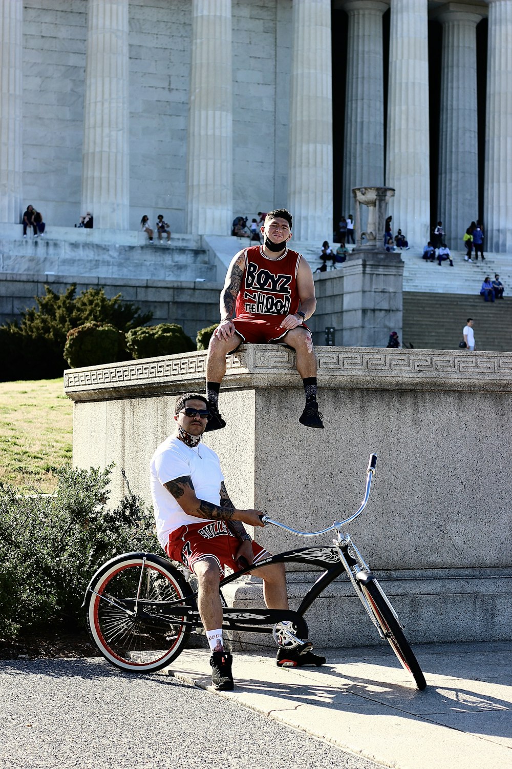 man in red and white tank top riding on red bicycle during daytime