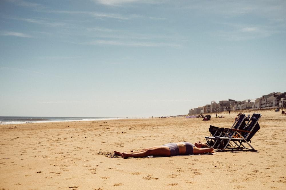woman in black bikini lying on brown sand during daytime