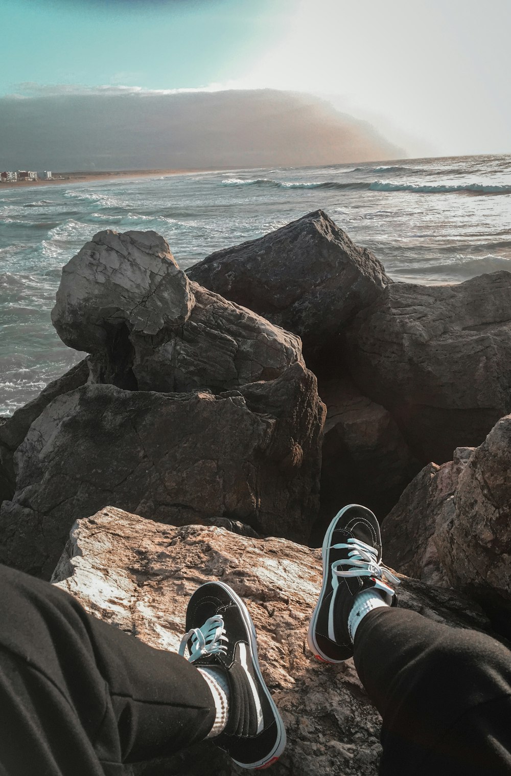 a person sitting on a rock near the ocean