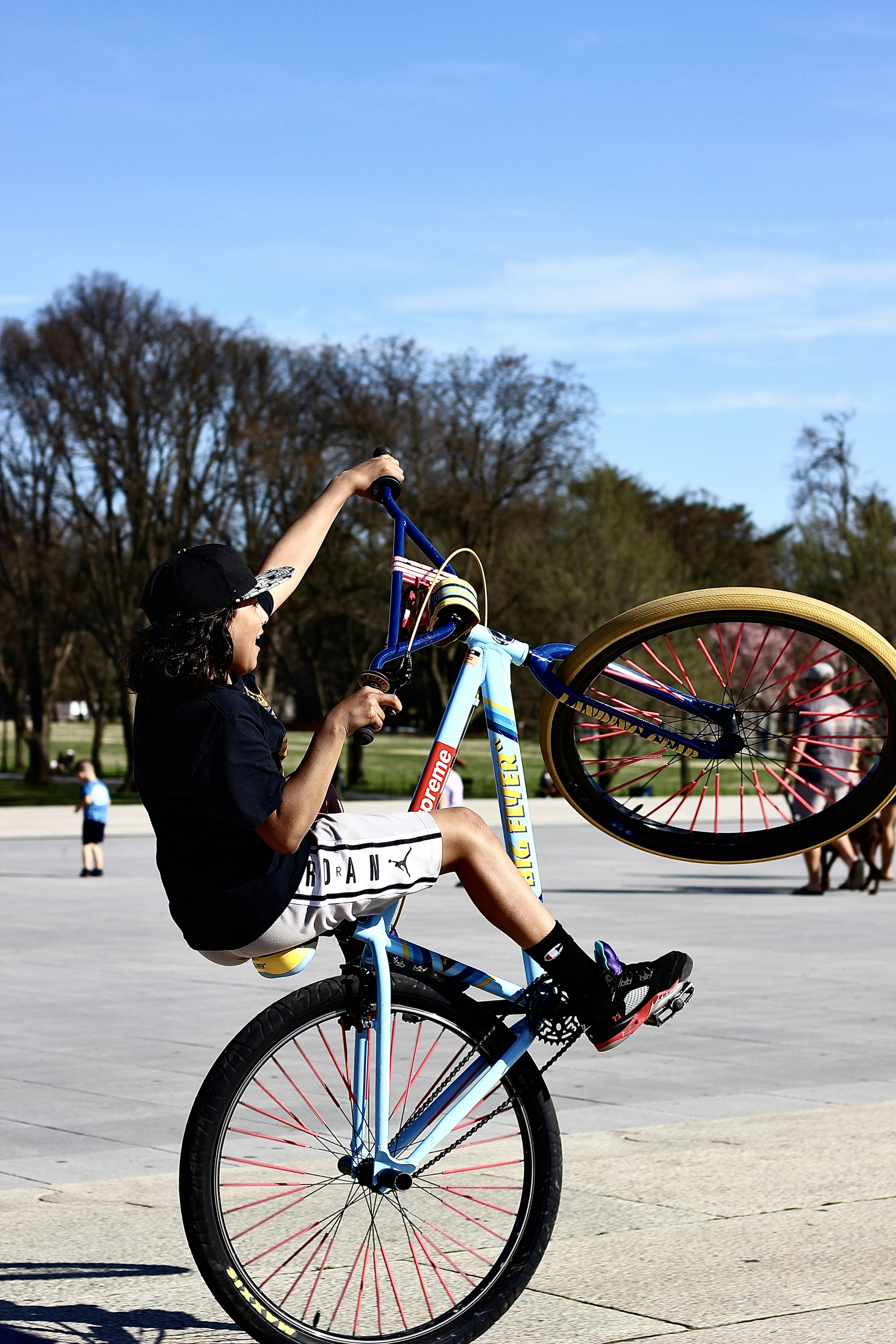 Hombre con camiseta negra y pantalones cortos azules montando en bicicleta azul y blanca durante el día