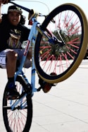 girl in white t-shirt and blue denim shorts riding on blue and red bicycle