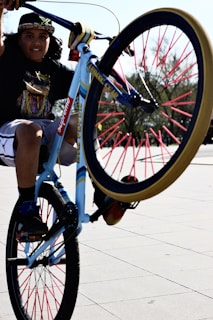 girl in white t-shirt and blue denim shorts riding on blue and red bicycle